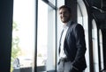 Confident young businessman looking at camera while standing near the window an office building. Royalty Free Stock Photo