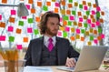 Confident young businessman sitting with laptop against window at office Royalty Free Stock Photo