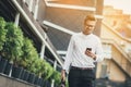 Confident young businessman using cell phone in the city. Sunshine background Royalty Free Stock Photo