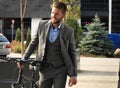 Confident young businessman walking with bicycle on the street in town. Royalty Free Stock Photo