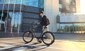 Confident young businessman walking with bicycle on the street in town. Royalty Free Stock Photo