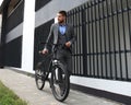 Confident young businessman walking with bicycle on the street in town. Royalty Free Stock Photo