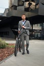 Confident young businessman walking with bicycle on the street in town. Royalty Free Stock Photo