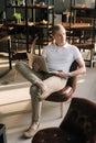 Confident young businessman wearing fashion casual clothing sitting on chair and holding laptop. Royalty Free Stock Photo