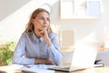 Confident young businesswoman with a friendly smile sitting at her desk in a home office Royalty Free Stock Photo