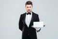 Confident young butler holding blank card on tray