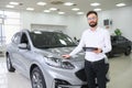 Confident young caucasian businessman shop assistant standing in car automobile dealer shop