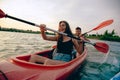 Confident young couple kayaking on river together with sunset on the background