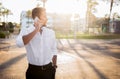 Confident young european businessman in formal outfit having business call on cellphone, standing outdoors, copy space Royalty Free Stock Photo