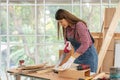 Confident young female carpenter cutting wood with a handsaw in the carpentry shop Royalty Free Stock Photo