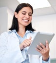 A confident, young female dentist working on her digital tablet in the doctors room. A beautiful and professional young Royalty Free Stock Photo