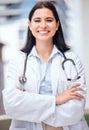 Confident young female doctor standing with her arms crossed outside a medical office. One caucasian woman in a white Royalty Free Stock Photo