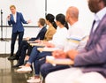 Confident female lecturer speaking to businesspeople at seminar