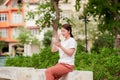 Confident young female student sitting on phone In park freely And intend ready in sun during sunset happy that day