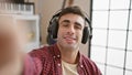 Confident young hispanic male musician, artist performing indoors, avidly listening to melody, passionately speaking on video call Royalty Free Stock Photo