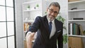 Confident young hispanic man, a grey-haired smiling worker, shaking hand in professional business agreement at office work Royalty Free Stock Photo