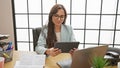 Confident young hispanic woman enjoying success as she works in the office, beautiful and happy business worker using laptop and Royalty Free Stock Photo