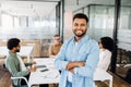 A confident young Indian male office employee in blue stands with his arms crossed Royalty Free Stock Photo