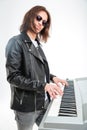 Confident young keyboardist in sunglasses standing and playing on synthesizer Royalty Free Stock Photo