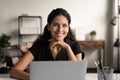 Confident young latin female posing by office computer at desk Royalty Free Stock Photo