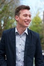 Confident young man in blue jacket, smiling outdoors Royalty Free Stock Photo