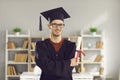 Happy university graduate standing in classroom, holding diploma and smiling at camera Royalty Free Stock Photo