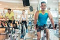 Confident young man smiling during indoor cycling class in a modern fitness club