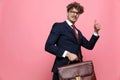 Confident young man in suit holding suitcase and making thumbs up gesture Royalty Free Stock Photo
