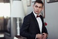 Confident young man in tuxedo with bow tie and boutonniere posing at camera holding his blazer Royalty Free Stock Photo