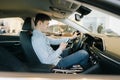 Confident young man using mobile phone sits behind wheel of car Royalty Free Stock Photo
