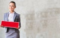 Portrait of confident young saleswoman holding sold placard while standing against wall in apartment