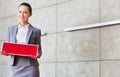 Portrait of confident young saleswoman holding sold placard while standing against wall in apartment