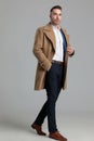 Confident young smartcasual guy in longcoat walking