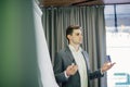 Confident young team leader or manager standing in front of a flip chart and present project on office Royalty Free Stock Photo