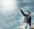 Confident young wearing a pair of VR glasses standing above the city on the rooftop building with the blue sky background excited