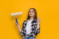 Confident Young Woman Is Holding Paint Roller And Pointing Up