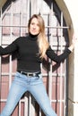 Confident young woman posing against windows ancient wall