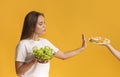 Confident young woman refusing plate with junk food and choosing salad Royalty Free Stock Photo