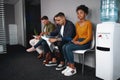 Young woman looking confident while sitting with a diverse group of job applicants in an office waiting for interviews