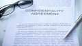 Confidentiality agreement, lying on table, pen and eyeglasses on document