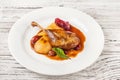 Confit duck leg in a restaurant close-up. Duck leg with pear in wine on a white plate and copy space