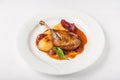 Confit duck leg in a restaurant close-up. Duck leg with pear in wine on a white plate and copy space