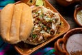 Confit pork sandwich called Torta de carnitas on wooden background. Mexican food