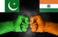 Conflict between India and Pakistan, male fists with flags painted on skin isolated on black background