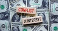 `Conflict of interest` words on wooden blocks. Business concept. Beautiful background from dollar bills. Copy space