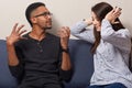 Conflict of multiethnic family. Desperate woman covers both ears, ignores husbands explanation or shouting, pose on sofa in