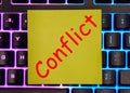 conflict text on a yellow piece of paper on the keyboard