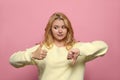 Conflicted young woman showing thumbs up and down gestures on pink background