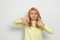 Conflicted young woman showing thumbs up and down gestures on white background