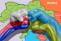 Conflicting hands with the texture of the flag of Russia and Ukraine. In the background is a map of Russia and Ukraine, as well as